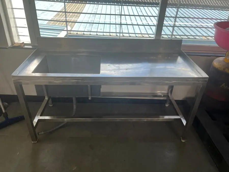 Stainless steel sink and table run fabricated against a wall