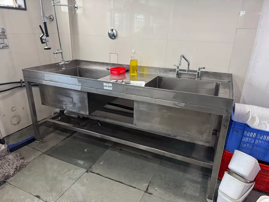 Double-bowl stainless steel sink unit with taps and drainboard